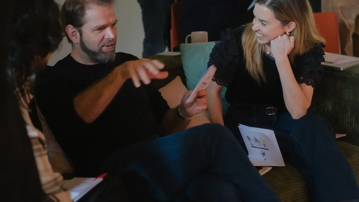 Two designers in conversation during a team session, one holding the Creative Archetypes booklet