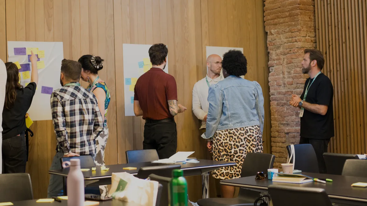 A group working a wall of sticky notes together, mid-discussion, in the same session